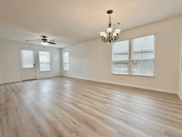 a view of an empty room with a window and wooden floor