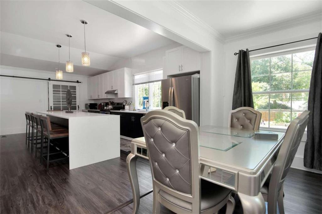 a kitchen with kitchen island a dining table chairs stainless steel appliances and windows