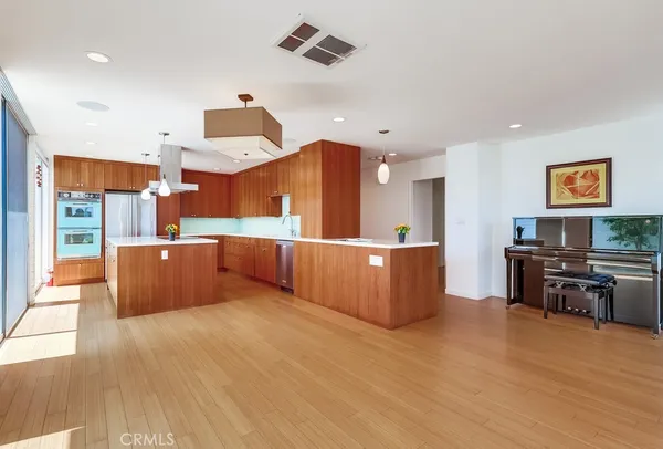 a large kitchen with stainless steel appliances wooden floors and large window