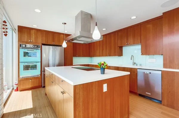 a large kitchen with stainless steel appliances kitchen island wooden floors and a large window