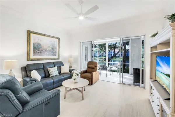a living room with furniture a flat screen tv and a floor to ceiling window