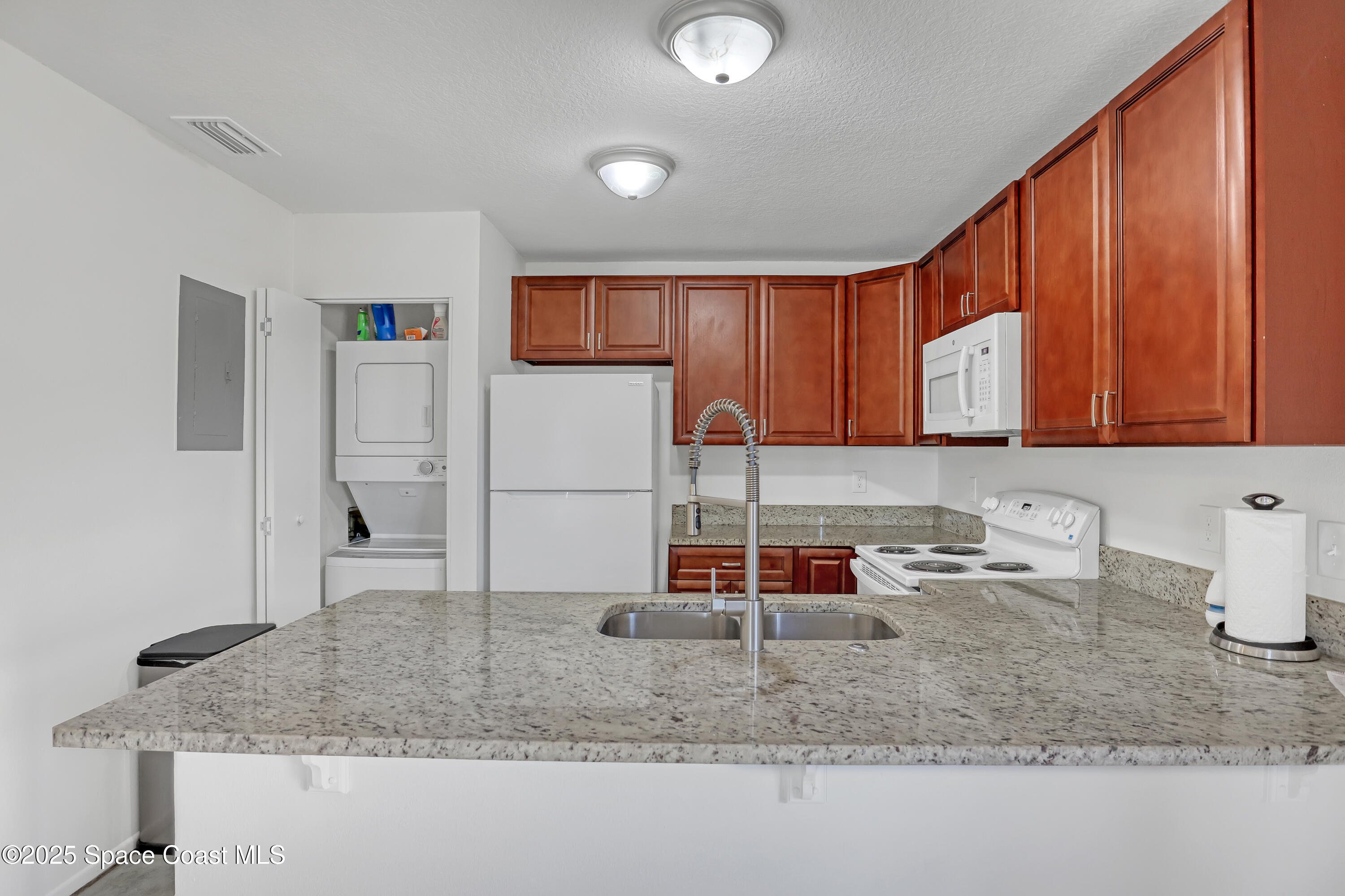 1031 Abada Court Northeast, Unit 110 Palm Bay, FL 32905 - Photo 14 of 33 a kitchen with kitchen island granite countertop a sink a stove and cabinets