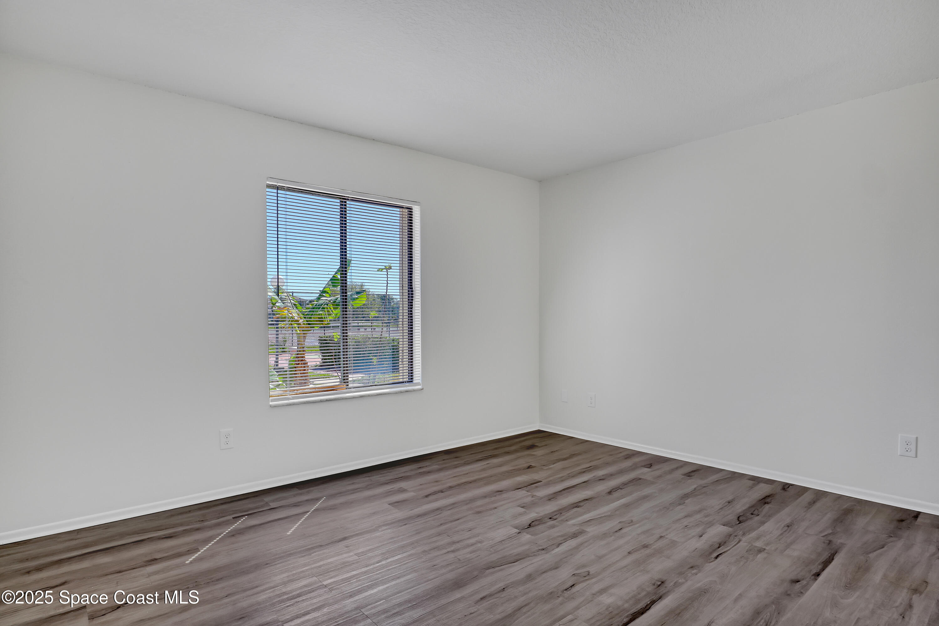 1031 Abada Court Northeast, Unit 110 Palm Bay, FL 32905 - Photo 18 of 33 a view of an empty room with wooden floor and a window