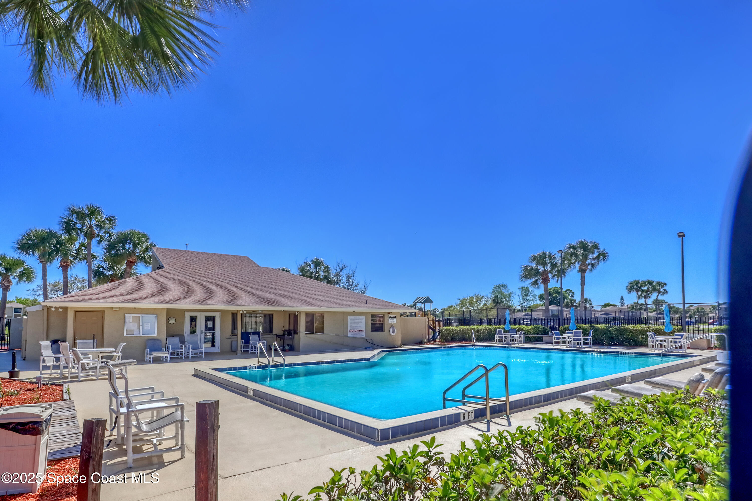 1031 Abada Court Northeast, Unit 110 Palm Bay, FL 32905 - Photo 32 of 33 a view of a swimming pool with lawn chairs under an umbrella
