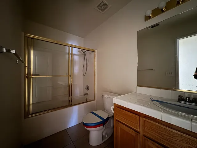 a bathroom with a granite countertop sink toilet and shower