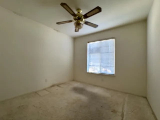 an empty room with a ceiling fan and window