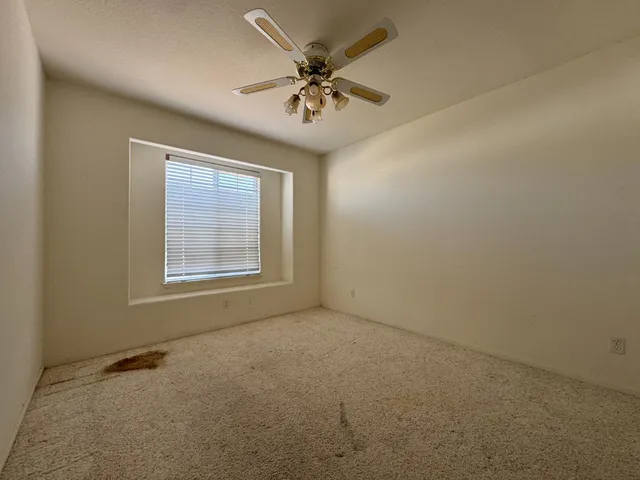 an empty room with a ceiling fan and window