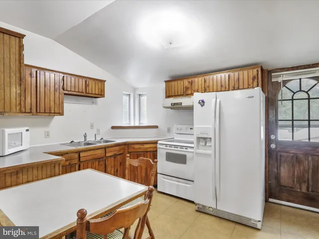 a kitchen with stainless steel appliances a refrigerator a sink a stove a table and chairs