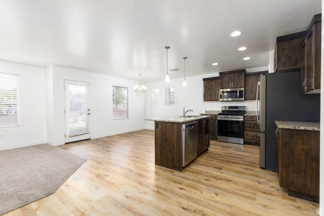 3157 Deseret Drive St. George, UT 84790 - Photo 4 of 24 Open-concept living space featuring wood-finish flooring, a kitchen island with pendant lighting, stainless steel appliances, dark wood-finish cabinetry, and recessed lighting