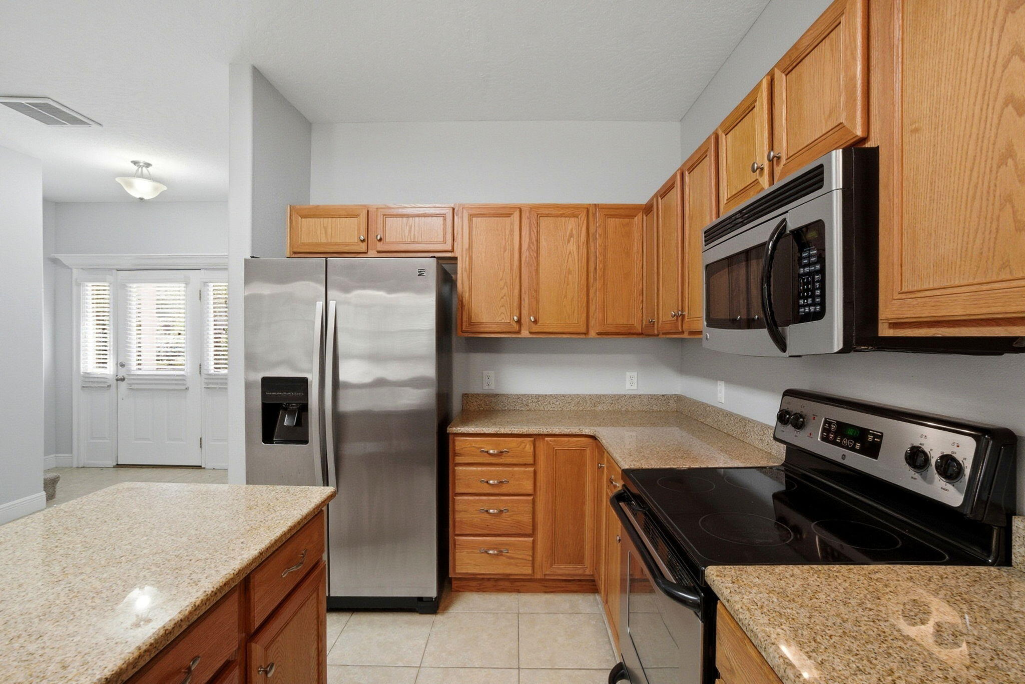 8562 Laredo Street Navarre, FL 32566 - Photo 10 of 43 a kitchen with granite countertop a refrigerator stove and microwave
