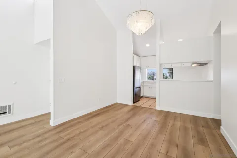 a view of a room with wooden floor and way to kitchen