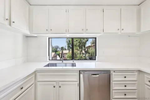 a sink with white cabinets and a window