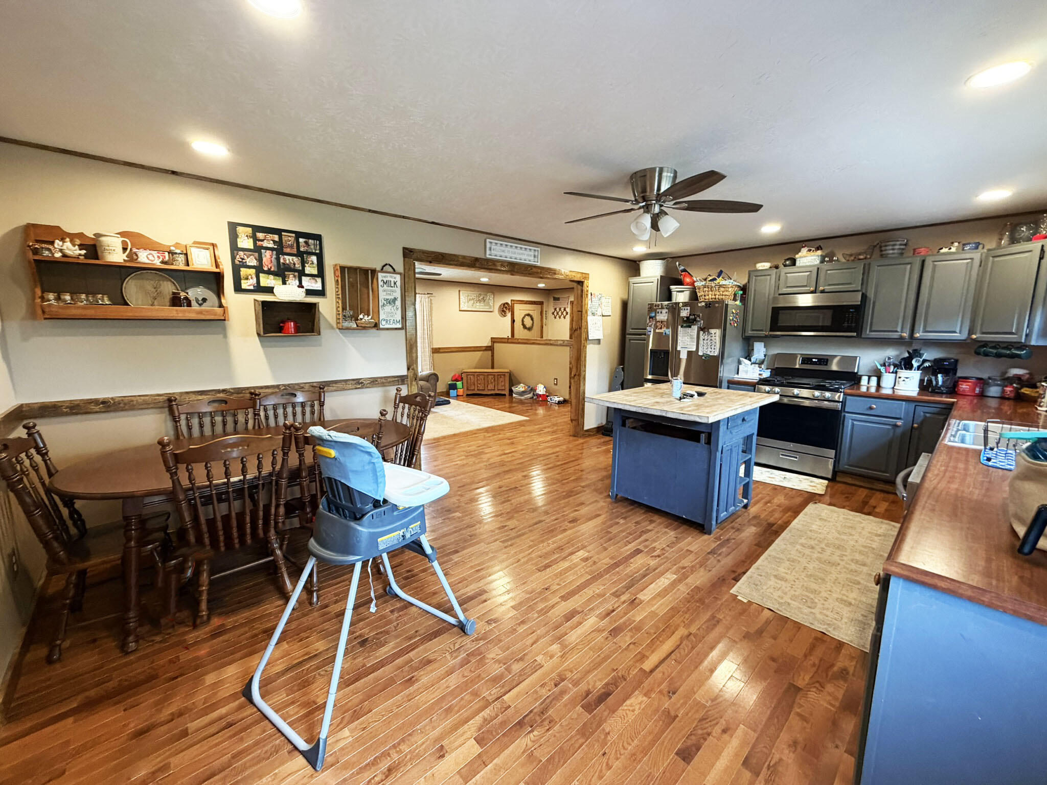 1410 Winston Road Irvine, KY 40336 - Photo 16 of 43 Eat-in kitchen featuring a center island, natural gas range, abundant cabinetry, hardwood flooring, Columbia Natural Gas service, and direct access to the large rear deck and grilling area, perfect for indoor and outdoor entertaining!