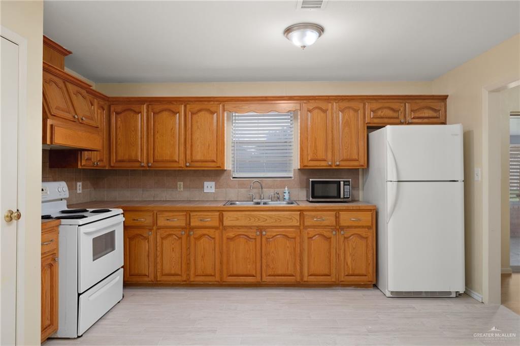 300 North 41st Street McAllen, TX 78501 - Photo 5 of 13 a kitchen with granite countertop a refrigerator a stove a sink and dishwasher