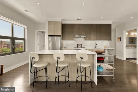 a kitchen with stainless steel appliances a table and chairs in it