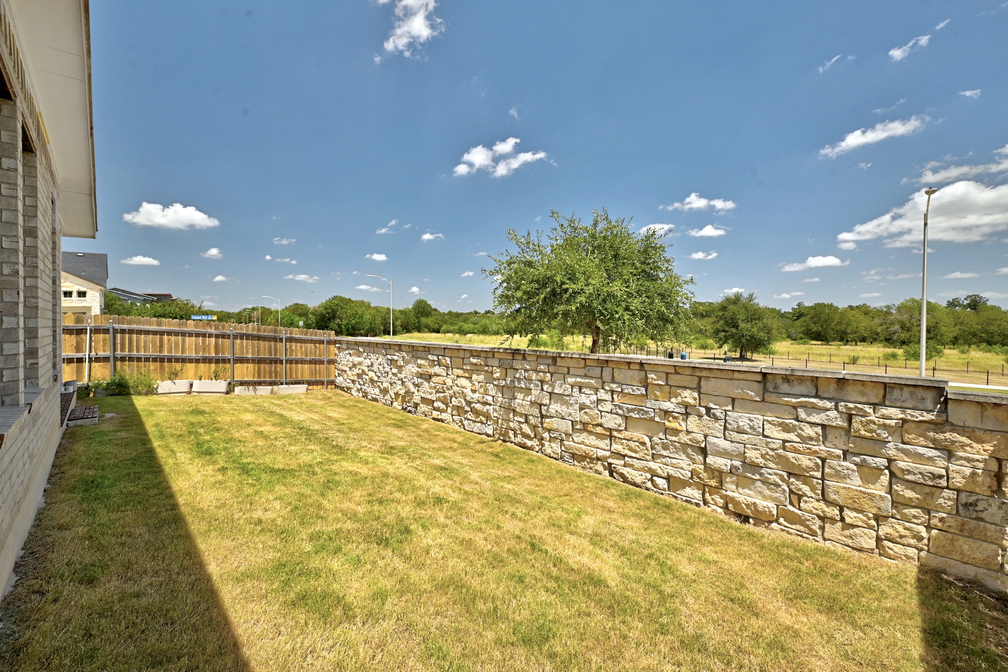 2702 Sebring Circle Austin, TX 78747 - Photo 28 of 35 A stone retaining wall defines the perimeter of this grassy yard under blue skies.