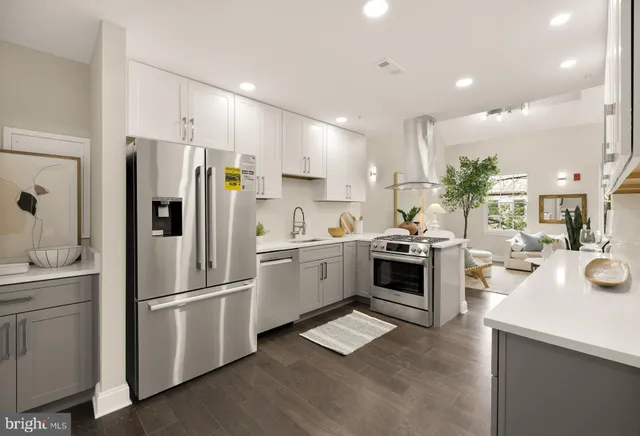 a kitchen with a refrigerator a sink and a stove top oven with wooden floor