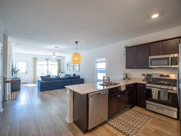 a kitchen with stainless steel appliances granite countertop a sink a stove and a wooden floors