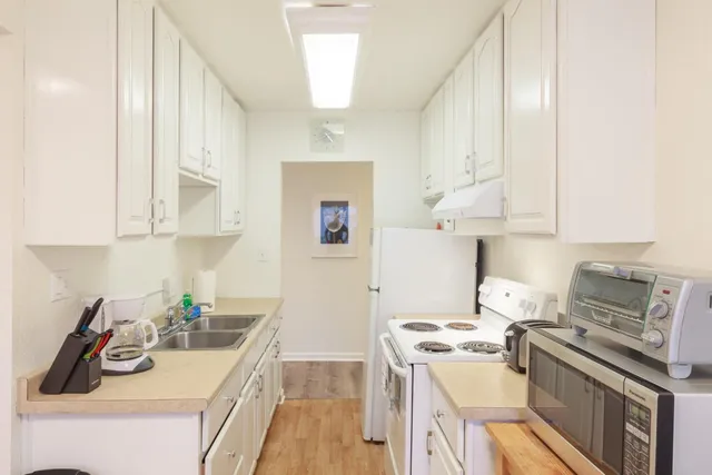 a kitchen with white cabinets and wooden floor