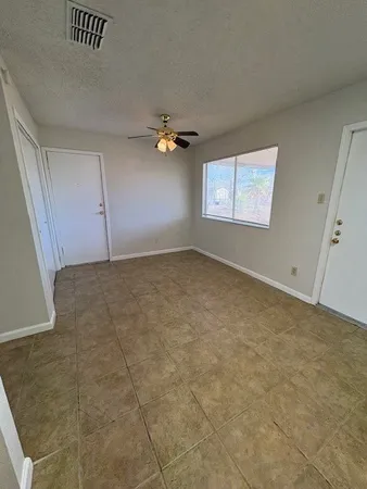 an empty room with windows and fan