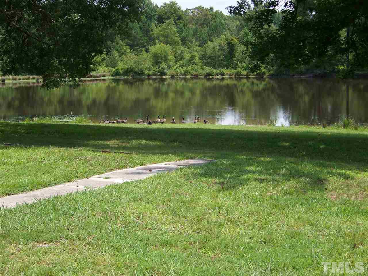 2114 Sanders Road Stem, NC 27581 - Photo 7 of 23 a view of a lake with a yard and large trees
