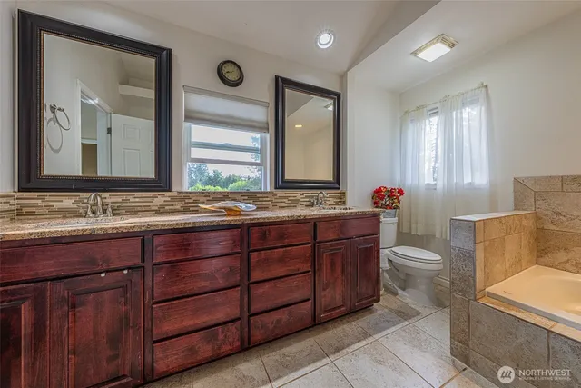 a bathroom with a granite countertop toilet sink and mirror