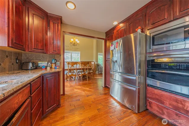 a kitchen with stainless steel appliances granite countertop a refrigerator a stove and a sink with wooden cabinets