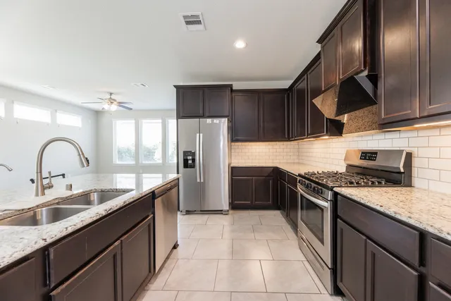 a kitchen with stainless steel appliances granite countertop a sink stove and refrigerator