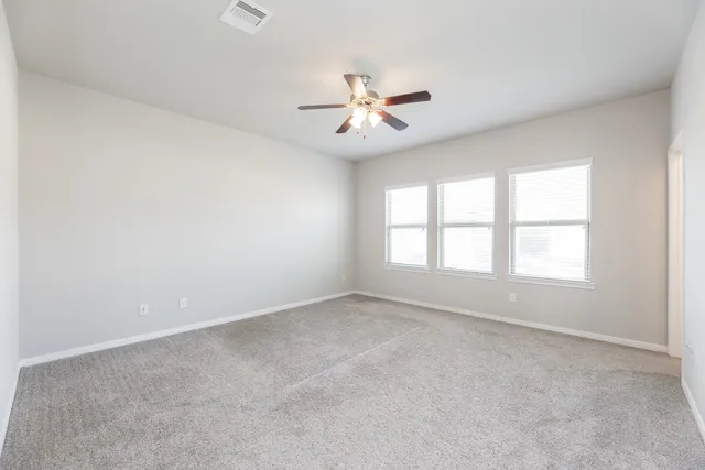 an empty room with windows and fan