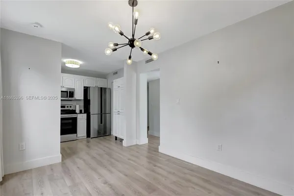 a view of a kitchen with a refrigerator a ceiling fan and wooden floor