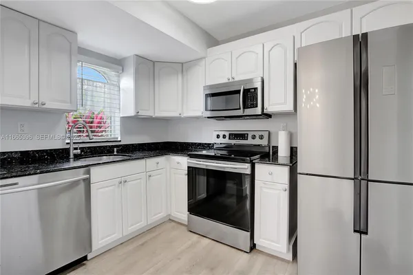 a kitchen with white cabinets stainless steel appliances and a sink