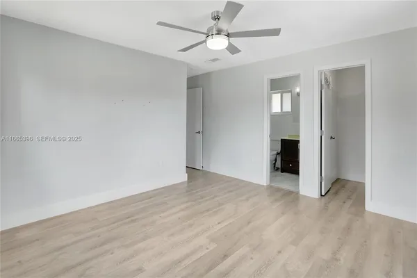an empty room with wooden floor and ceiling fan