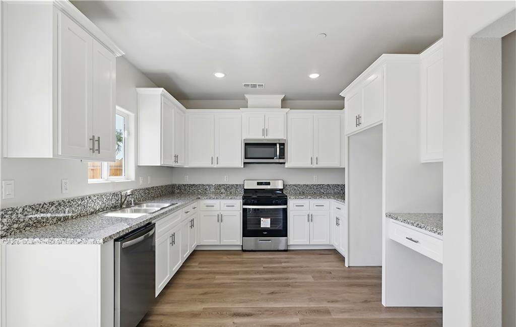 a large kitchen with stainless steel appliances granite countertop a stove top oven a sink and dishwasher