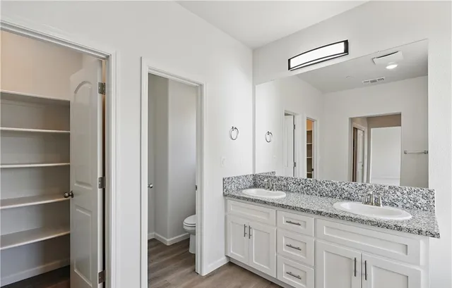a bathroom with a granite countertop double vanity sink and a mirror