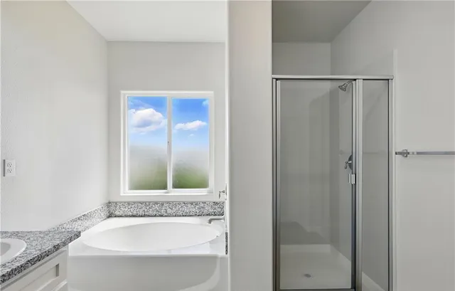 a bathroom with a granite countertop tub sink and mirror