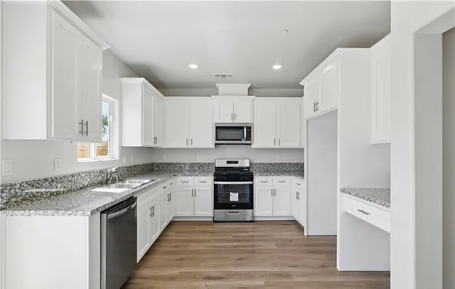 a large kitchen with stainless steel appliances granite countertop a stove top oven a sink and dishwasher