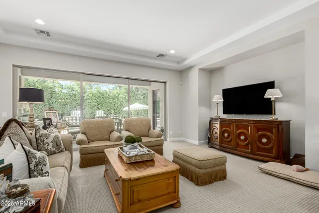 a living room with furniture a flat screen tv and floor to ceiling window