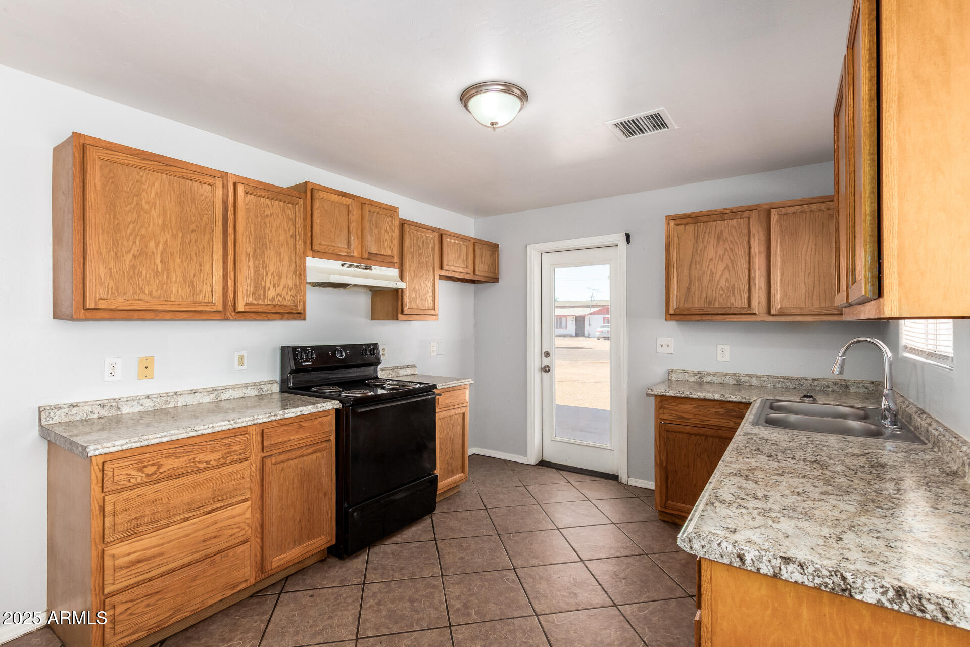 105 West 8th Street Eloy, AZ 85131 - Photo 13 of 31 a kitchen with granite countertop wooden cabinets and a stove top oven