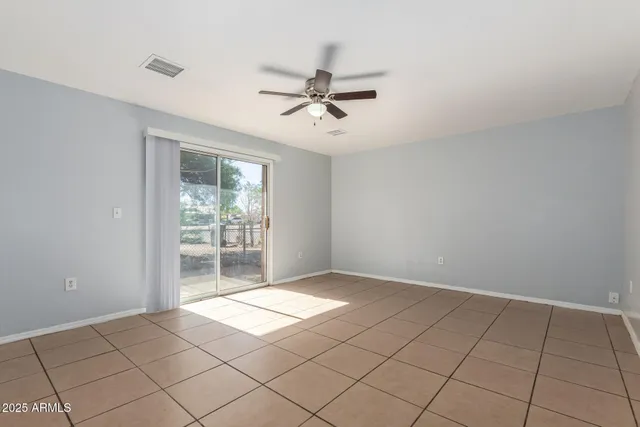 a view of an empty room and window & chandelier fan