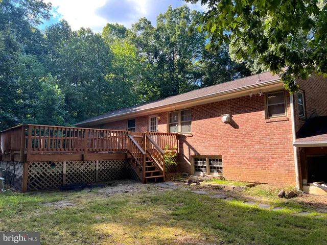a view of a deck with a big yard and a large tree