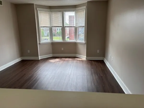 an empty room with wooden floor and windows