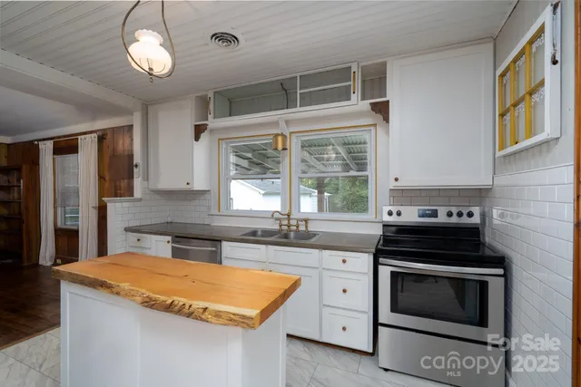 a kitchen with stainless steel appliances granite countertop a stove a sink and a microwave