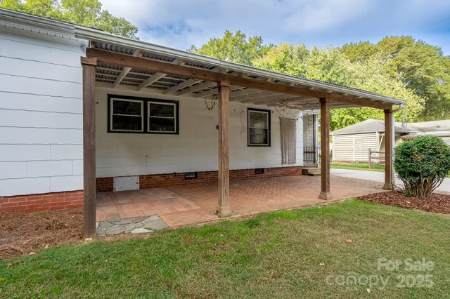 a view of a backyard with couches plants and large trees with wooden fence