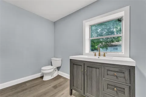 a bathroom with a granite countertop toilet a sink and a window