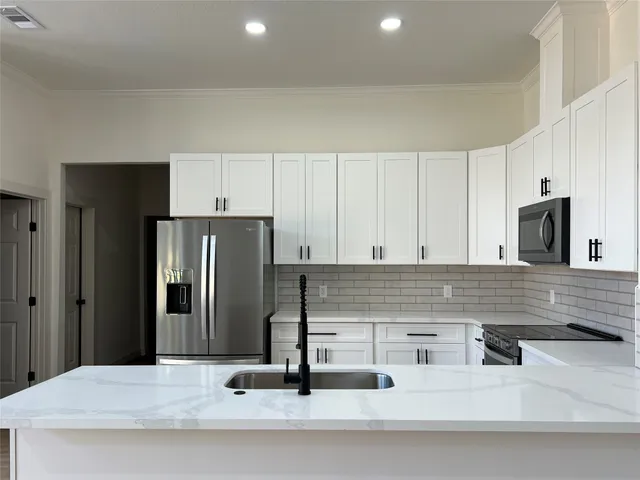 a kitchen with stainless steel appliances kitchen island granite countertop a refrigerator and a sink