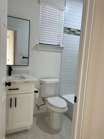 a bathroom with a granite countertop toilet sink and mirror