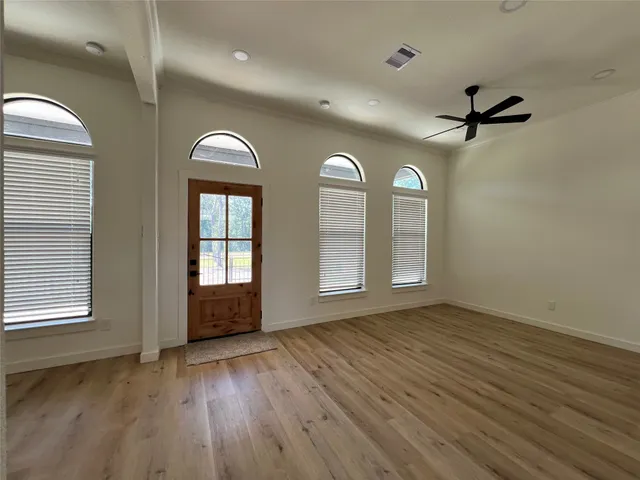 an empty room with wooden floor mirror and windows