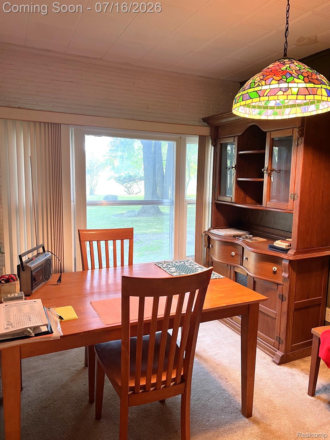 904 West Lovejoy Road Perry, MI 48872 - Photo 6 of 21 Dining area featuring a large window, a wood-finish hutch, and a stained-glass pendant light fixture