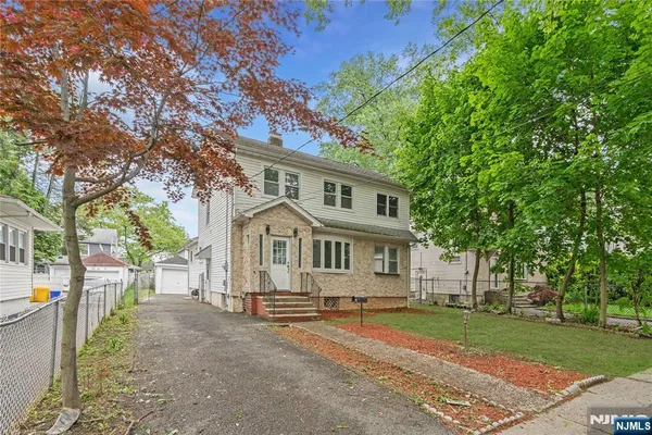 a view of a white house next to a yard with big trees