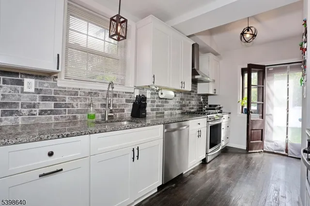a kitchen with a sink dishwasher a stove and white cabinets with wooden floor